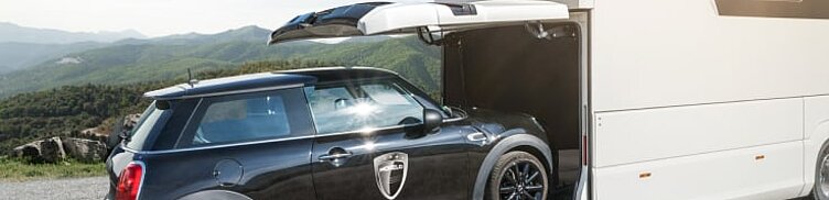 Außenaufnahme des Wohnmobils Morelo Empire Liner mit Blick auf die Heckgarage und einem einparkenden Fahrzeug.