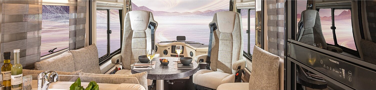 Innenaufnahme aus dem Wohnmobil Concorde Credo mit Blick auf den Essbereich und das Cockpit.