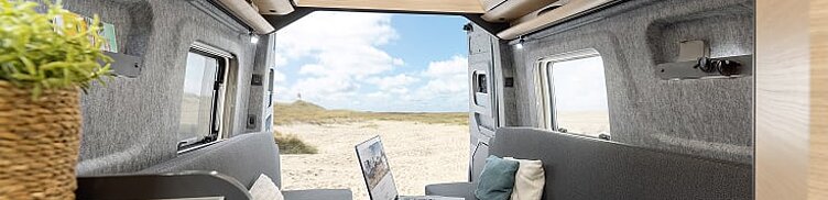 Innenansicht des Kastenwagens Hobby Maxia Van mit Blick in den Essbereich und das geöffnete Heck..