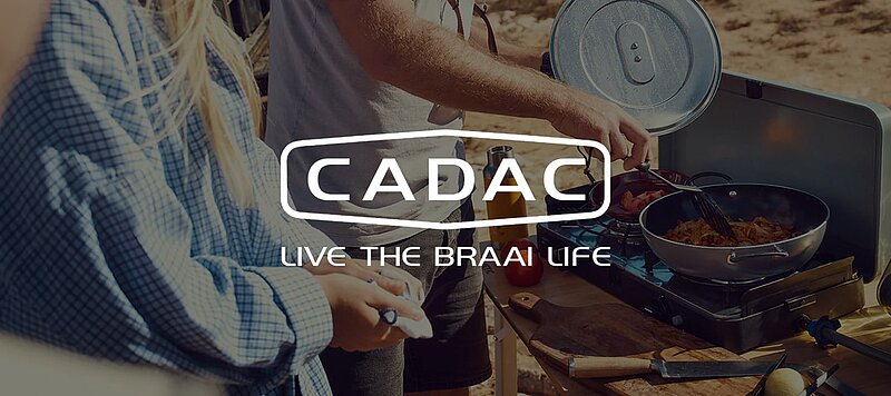 Junges Pärchen beim Grillen mit einem Cadac-Campinggrill in einer sonnigen Strandumgebung. Über dieses Motiv wurde das Logo von Cadac platziert mit dem Slogan "Live the Braai life". Junges Pärchen beim Grillen mit einem Cadac-Campinggrill in einer sonnigen Strandumgebung. Über dieses Motiv wurde das Logo von Cadac platziert mit dem Slogan "Live the Braai life".