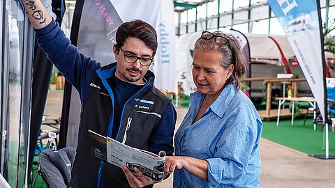 Beratungsgespräch zwischen einem Mitarbeiter von Caravaning Center Schmidtmeier und einer interessierten Kundin an einem aufgebauten Zelt.