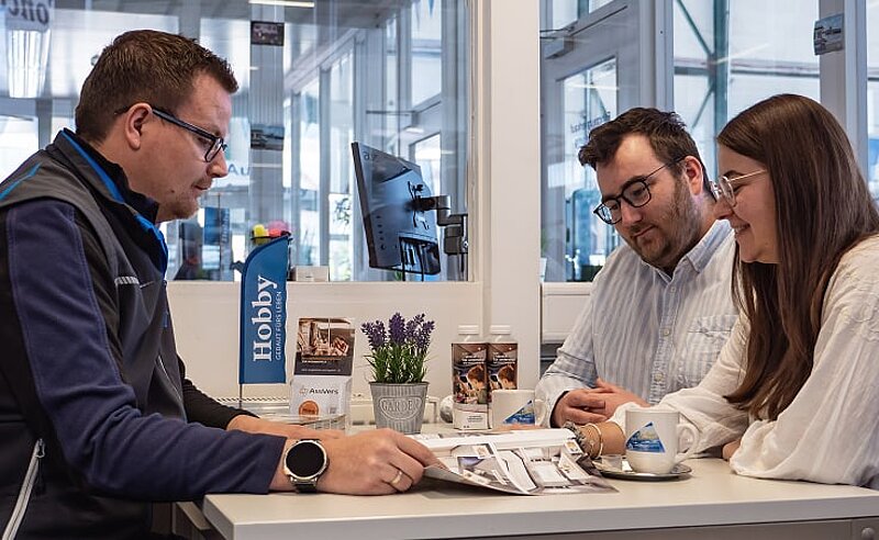 Beratungsgespräch zwischen einem Mitarbeiter von Caravaning Center Schmidtmeier und einem interessierten Pärchen in einem Büro. Beratungsgespräch zwischen einem Mitarbeiter von Caravaning Center Schmidtmeier und einem interessierten Pärchen in einem Büro.