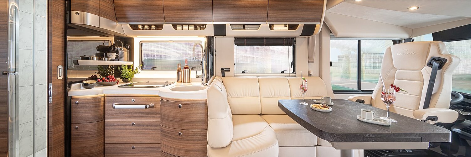 Innenaufnahme aus dem Wohnmobil Concorde Charisma mit Blick auf die Küche sowie den Wohnbereich und das Cockpit.