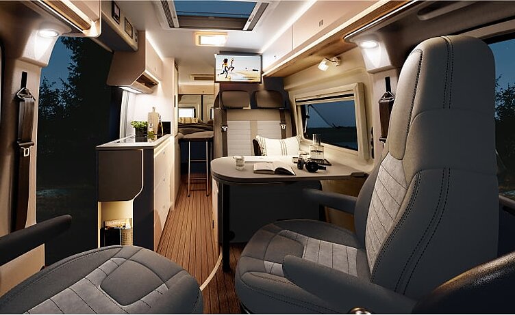 Innenansicht des Kastenwagens Hobby Prestige Van mit Blick in den Essbereich vom Cockpit aus bei Nacht.