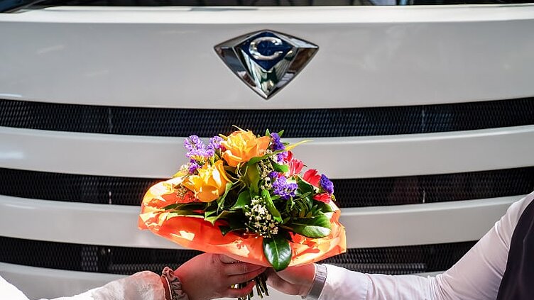 Nahaufnahme einer Übergabe eines Blumenstraußes vor einem Concorde Wohnmobil